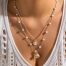 Layered long gold necklace with pearl and seashell charms displayed on white background